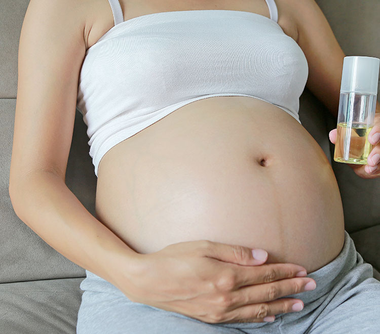donna in gravidanza applica olio sulla pancia per prevenire le smagliature